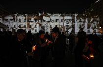 Люди зажигают свечи перед портретами людей, задержанных и исчезнувших во время диктатуры Пиночета в 1973-1990 годах