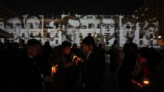 Personas encienden velas frente a los retratos de personas detenidas y desaparecidas durante la dictadura del general Augusto Pinochet (1973-1990).