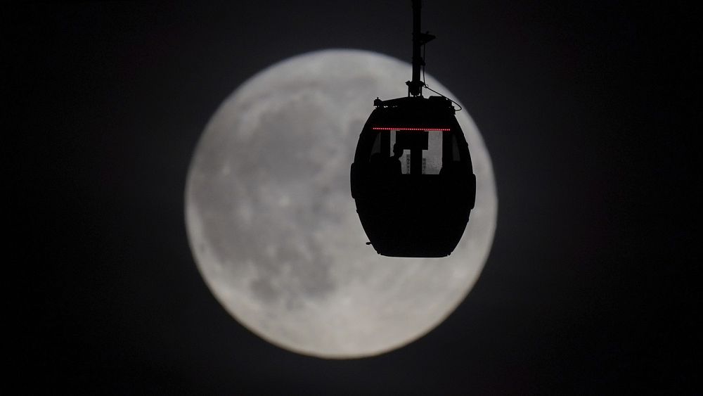 Хората гледат Супер синята луна, докато пътуват в облачен кабинков