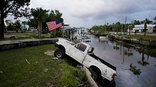 A pickup truck with an American flag tied to sits halfway into a canal in Horseshoe Beach, Fla., after the passage of Hurricane Idalia, Wednesday, Aug. 30, 2023. 