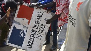 Protesters hold a sign taken from the French Embassy in Niamey during a demonstration that followed a rally in support of Niger's junta.