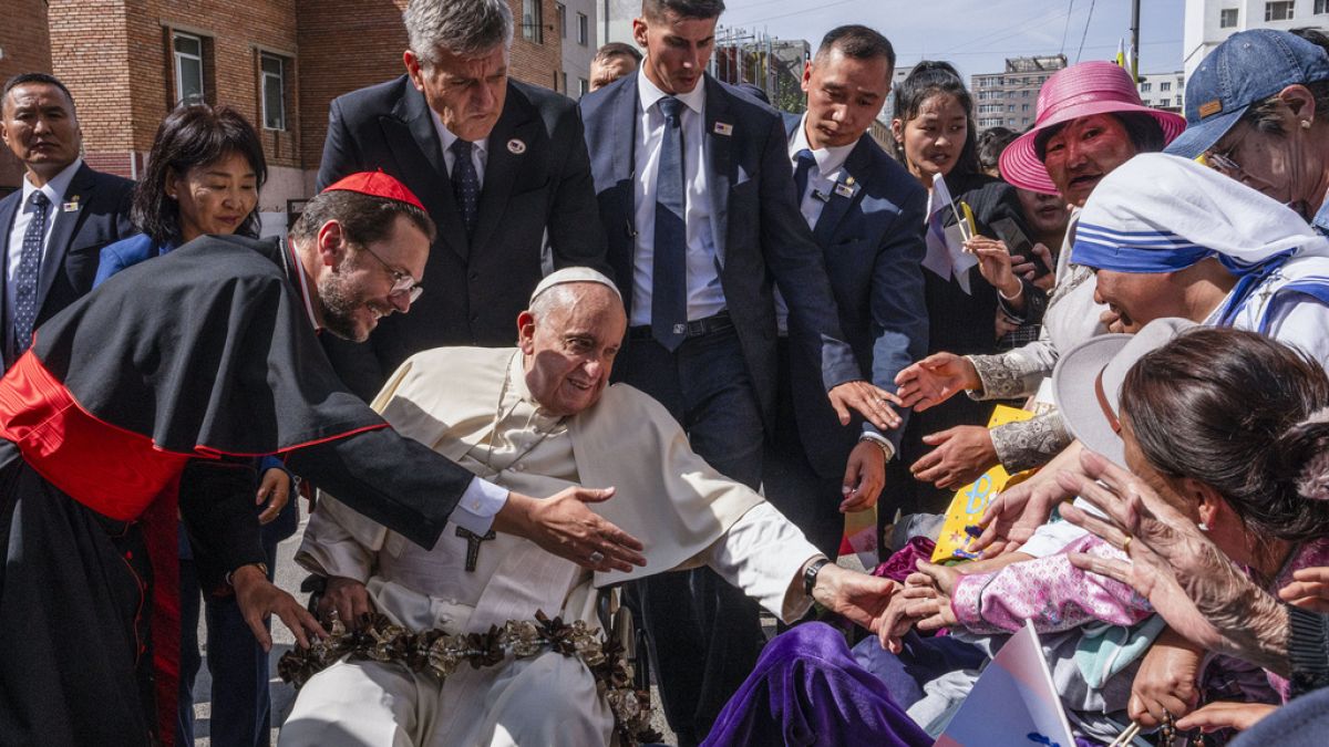 Pope Francis is greeted by Cardinal Giorgio Marengo, left, Apostolic Prefect of Ulaanbaatar, and faithful gathered outside the Apostolic Prefecture, Sept 1, 2023 