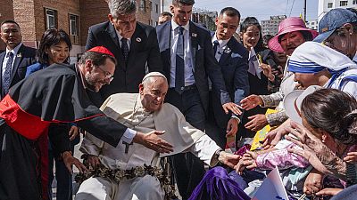 Pope Francis is greeted by Cardinal Giorgio Marengo, left, Apostolic Prefect of Ulaanbaatar, and faithful gathered outside the Apostolic Prefecture, Sept 1, 2023