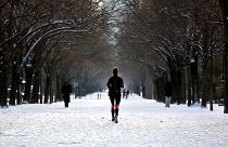 A woman runs down an alley covered with snow, in Paris, Wednesday, Feb. 10, 2021.