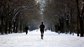 A woman runs down an alley covered with snow, in Paris, Wednesday, Feb. 10, 2021.
