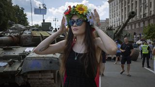 Mulher usa uma grinalda de flores em frente a tanques russos capturados, expostos no centro de Khreshchatyk, em Kiev, na Ucrânia. 24 de agosto de 2023