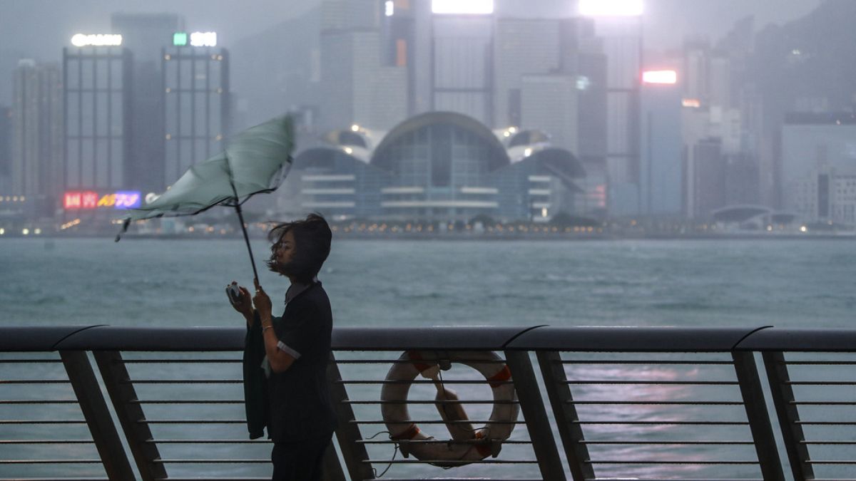 El paraguas de una mujer es arrastrado por el viento a la orilla del mar mientras el tifón Saola azota la ciudad, en Hong Kong, el viernes 1 de septiembre de 2023