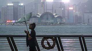 امرأة في هونغ كونغ تحاول الاحتماء من الرياح العاتية التي سببها إعصار ساولا