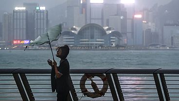 El paraguas de una mujer es arrastrado por el viento a la orilla del mar mientras el tifón Saola azota la ciudad, en Hong Kong, el viernes 1 de septiembre de 2023