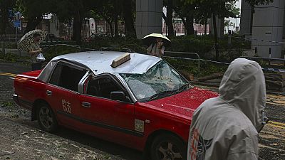 Residents look at a taxi damaged by Typhoon Saola in Chai Wan, Hong Kong, Saturday, Sept. 2, 2023.