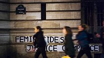 Fransa'nın başkenti paris'te Adalet Sarayı'nın önüne asılan "Suçlu devlet, suç ortağı adalet" yazılı pankartın önünden geçen kadınlar