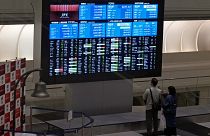 Visitors look at an electronic stock board at Tokyo Stock Exchange in Tokyo