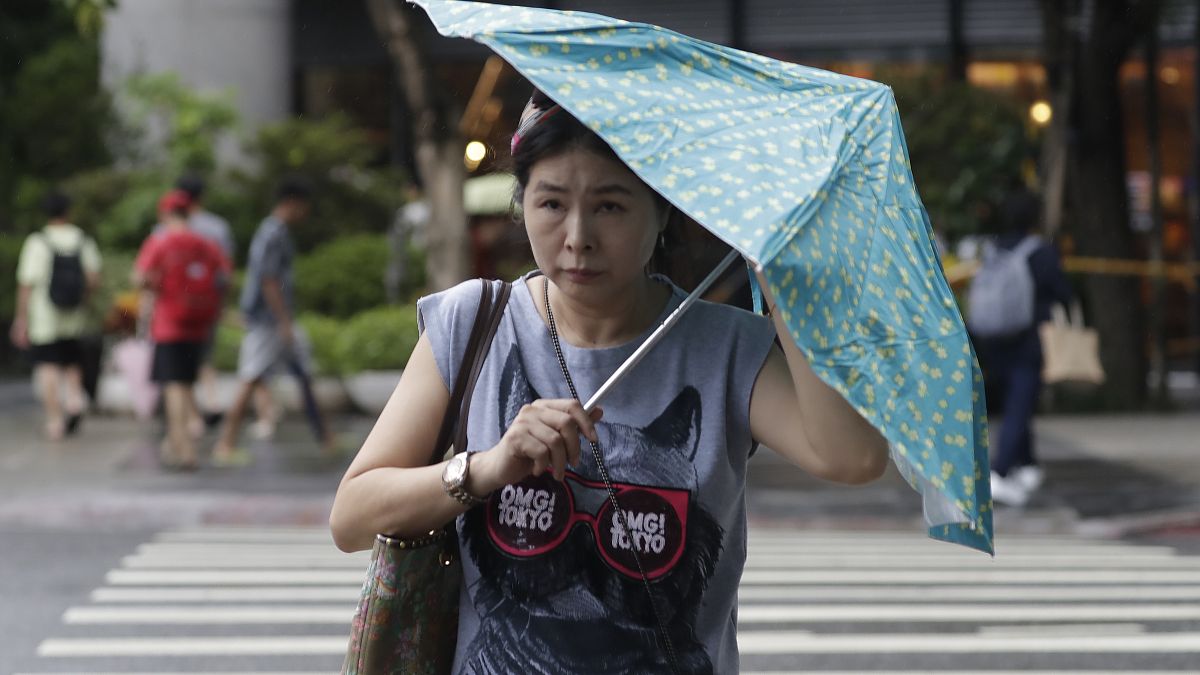 امرأة تكافح بمظلتها ضد هبوب الرياح الناتجة عن إعصار هايكوي في تايوان 