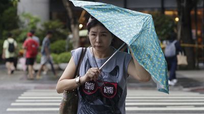 امرأة تكافح بمظلتها ضد هبوب الرياح الناتجة عن إعصار هايكوي في تايوان
