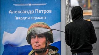 Moskova'da bir kişi otobüs durağında 'Rusya'nın kahramanlarına şan olsun' sloganı yazan posteri temizliyor, 24 Ekim 2022