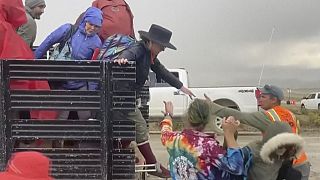 In this image from video provided by Rebecca Barger, festival goers are helped off a truck from the Burning Man festival site in Black Rock, Nev., on Monday, Sept. 4, 2023.
