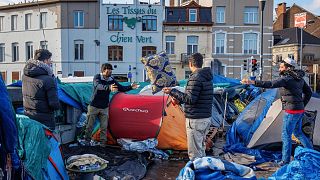 FILE - Men organize their belongings at a makeshift tent camp outside the Petit Chateau reception center in Brussels, on Jan. 17, 2023.