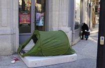Une femme se tient dans la rue à côté d'une tente de sans-abri, à Paris, France, mardi 21 décembre 2021. Les pays d'Europe ont décidé de réimposer des mesures plus strictes po