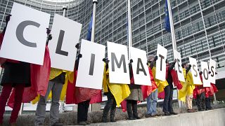 Protestors from Friends of the Earth hold up cards which read out 'Climate SOS' during a demonstration outside EU headquarters in Brussels on Wednesday, Jan. 22, 2014.