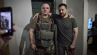 In this photo provided by the Ukrainian Presidential Press Office, Ukrainian President Volodymyr Zelenskyy, right, poses for a photo with serviceman.