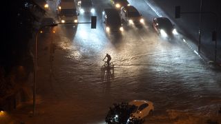 A cyclist rides through floodwater blocking the road due to heavy rain in Basaksehir district of Istanbul, Turkey, Tuesday, Sept. 5, 2023.