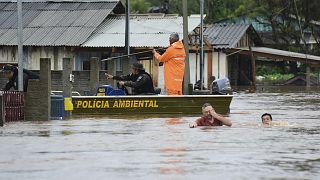 Policias verificam uma casa enquanto moradores atravessam uma rua inundada pela passagem de um ciclone, no Rio Grande do Sul, Brasil, 4 de setembro de 2023.