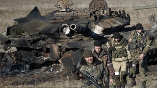 مقاتلون موالون لموسكو في الدونباس عام 2015 ووراءهم دبابة أوكرانية مدمرة