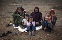 Uma família síria que fugiu da violência na sua aldeia está sentada no chão de um campo de deslocados na aldeia síria de Atmeh, perto da fronteira turca com a Síria.