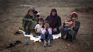 Uma família síria que fugiu da violência na sua aldeia está sentada no chão de um campo de deslocados na aldeia síria de Atmeh, perto da fronteira turca com a Síria.