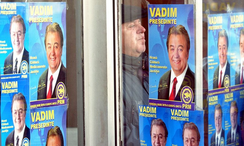 A supporter of nationalist leader Corneliu Vadim Tudor waits behind posters of the candidate before a rally in Ploiesti, November 2004