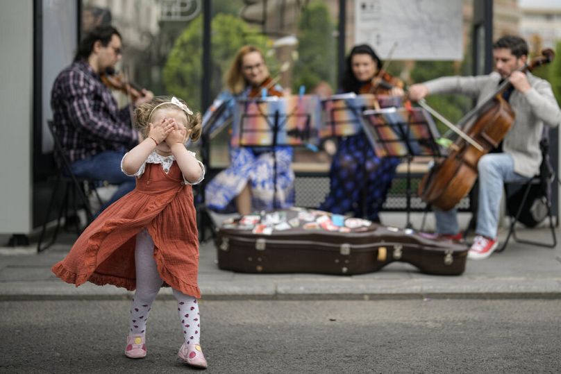 A little girl covers her eyes as a quartet performs classical music in a bus stop in Bucharest, May 2022