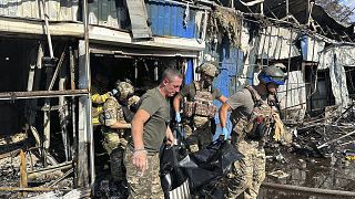 Украинские спасатели выносят тело погибшего