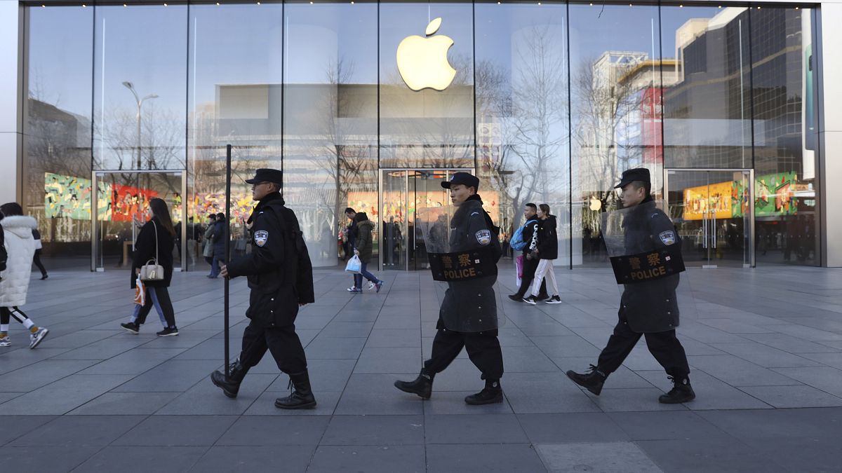 Chinese security guards march past an Apple store in Beijing, China.
