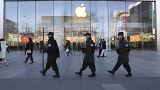 Çinli güvenlik görevlileri Pekin, Çin'deki bir Apple mağazasının önünden geçiyor.