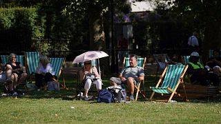 People bask in the hot weather in Green Park, central London, Monday Sept. 4, 2023. (Lucy North/PA via AP)
