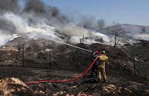 Os bombeiros tentam extinguir um incêndio numa fábrica de reciclagem, em Sesklo, no centro da Grécia, a 26 de julho de 2023\.