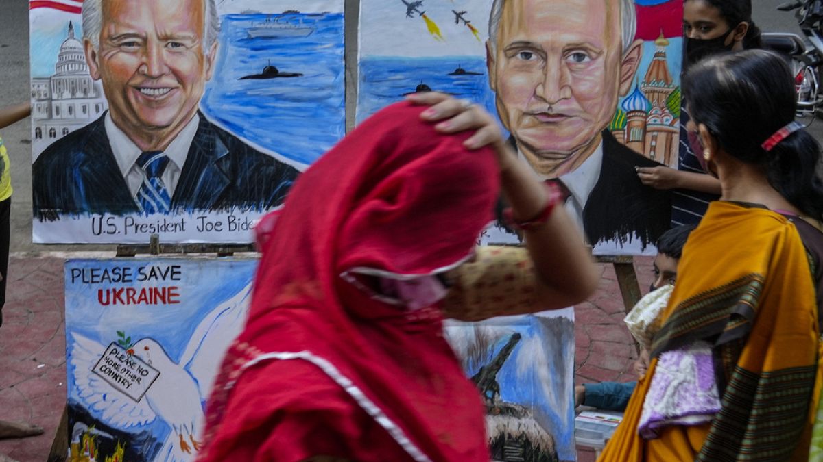 File - A woman adjusts her sari as she walks past art works by students calling for peace amid fears of a Russian offensive on Ukraine, on a pavement in Mumbai, India