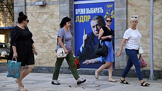 Women walk past a Russian Liberal Democratic Party poster with an image of former party leader Vladimir Zhirinovsky prior to local elections in Donetsk, eastern Ukraine.