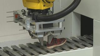 A machine carefully separates a trainer sole from the upper part of the shoe