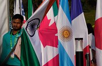 یک نفر در حال قرار دادن پرچم کشورهای شرکت کننده در اجلاس وزرای خارجه گروه بیست در هند در مارس ۲۰۲۳