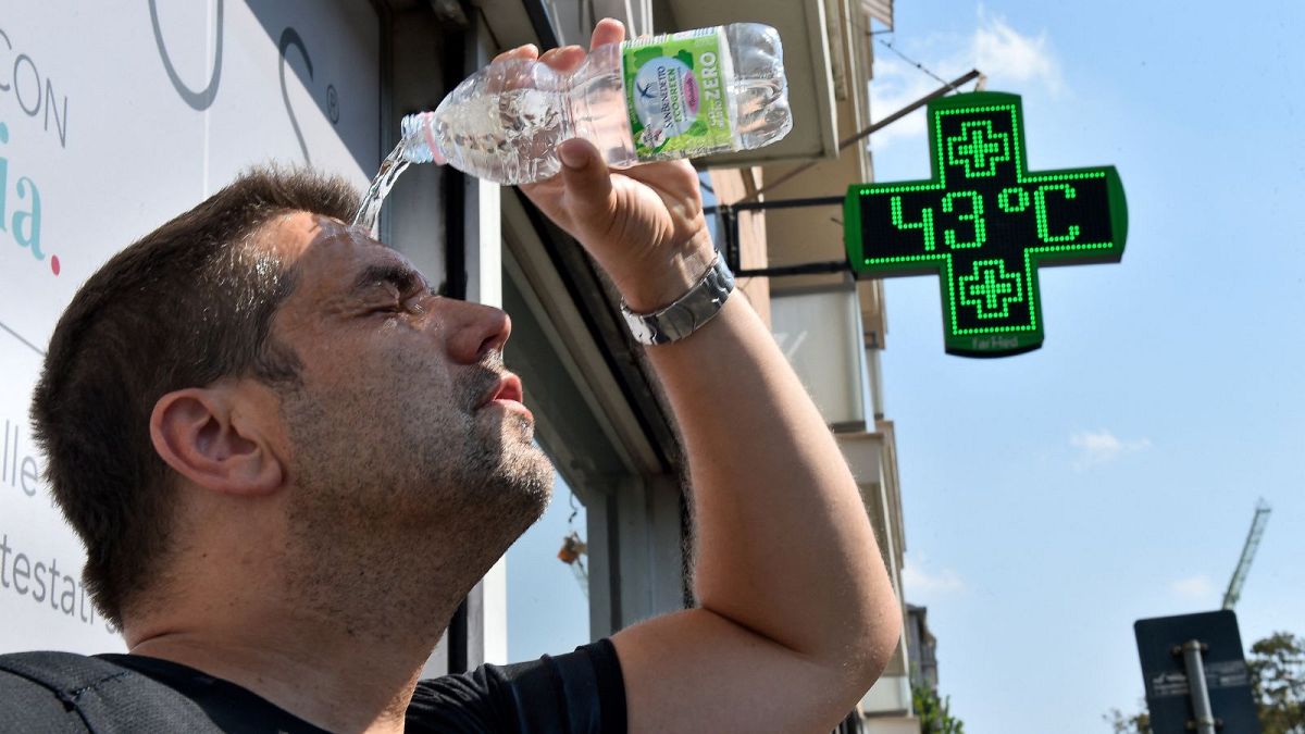 Um homem deita água sobre si próprio durante uma vaga de calor em Turim, Itália, a 25 de agosto de 2023.