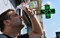 Um homem deita água sobre si próprio durante uma vaga de calor em Turim, Itália, a 25 de agosto de 2023.