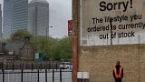Londra'nın doğusunda, Canary Wharf finans bölgesindeki yüksek binaların arkasında yürüyen bir adam.