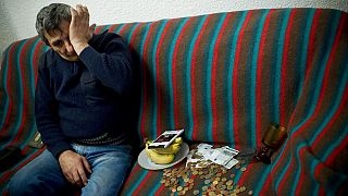 FILE: Gheorghe Lactu, 50 years-old, a citizen of Serbia, reacts, sitting in his rented house next to his coins collected after begging on the street.