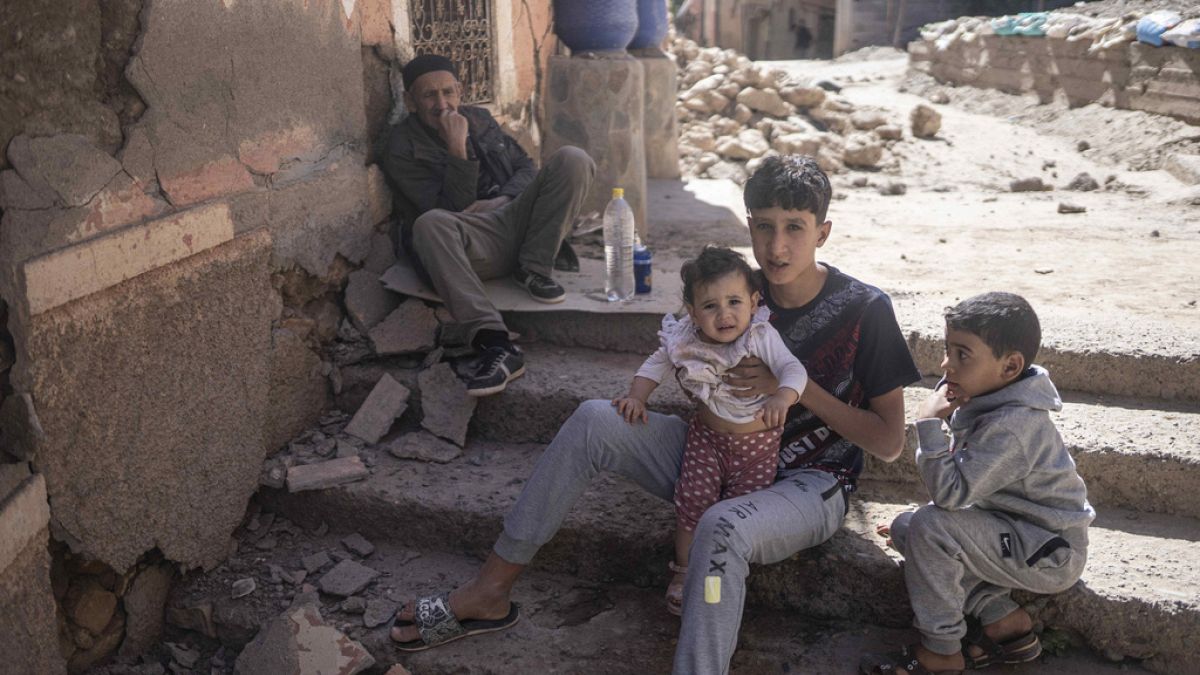 A family sits outside their home after an earthquake in Moulay Ibrahim village, near Marrakech, Morocco, Saturday, Sept. 9, 2023. 