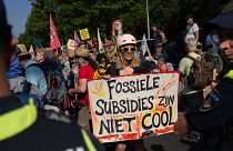 A protestor holds a sign reading "Fossil Subsidies Are Not Cool" as she blocks a highway near the Dutch parliament in The Hague, Netherlands, Sept. 9, 2023.