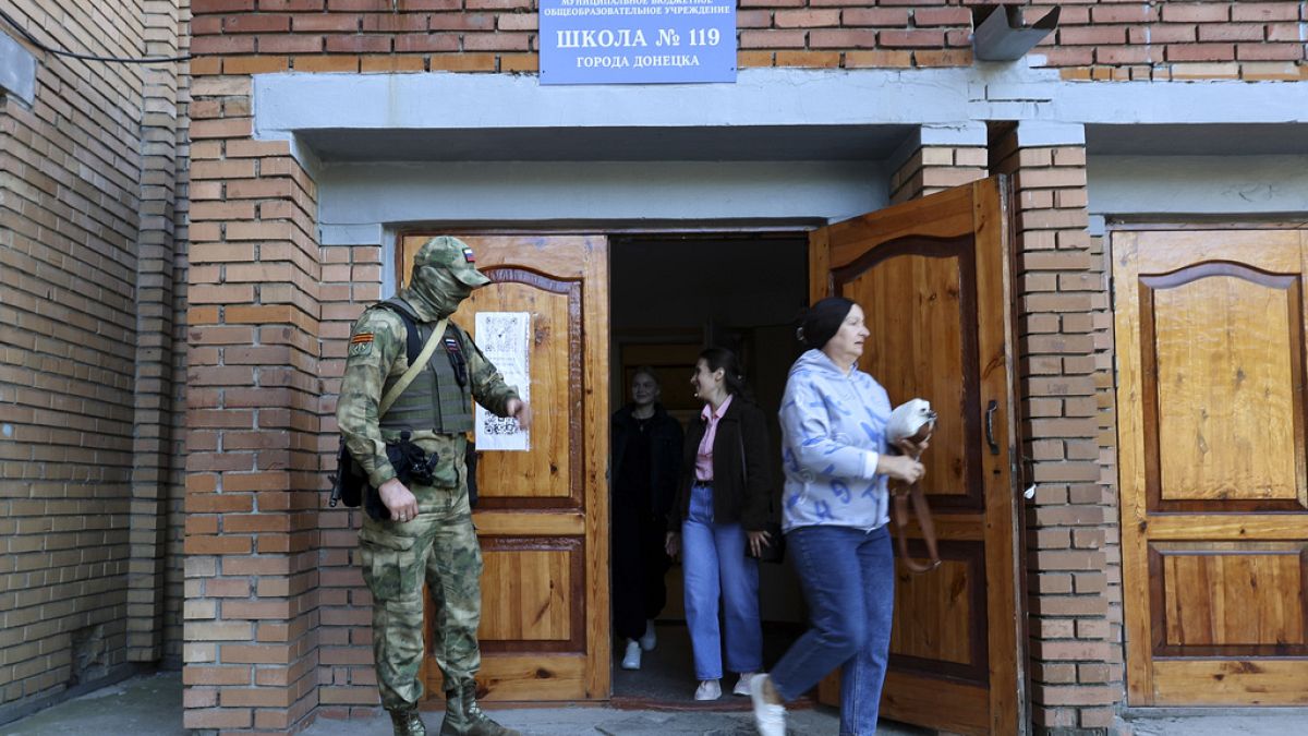 A serviceman guards an entrance of a polling station during a local elections in Donetsk, the capital of Russian-controlled Donetsk region, eastern Ukraine, on Sept. 10, 2023.
