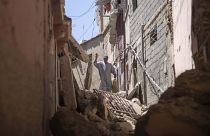 Un hombre saluda a sus amigos mientras camina entre los escombros causados por el terremoto, en Amizmiz, cerca de Marrakech, Marruecos, el domingo 10 de septiembre de 2023.