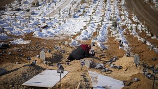 A woman cries over the graves of her son and daughter, killed during the earthquake of February 2023, at Sehir cemetery in Malatya, Sunday, Feb. 12, 2023