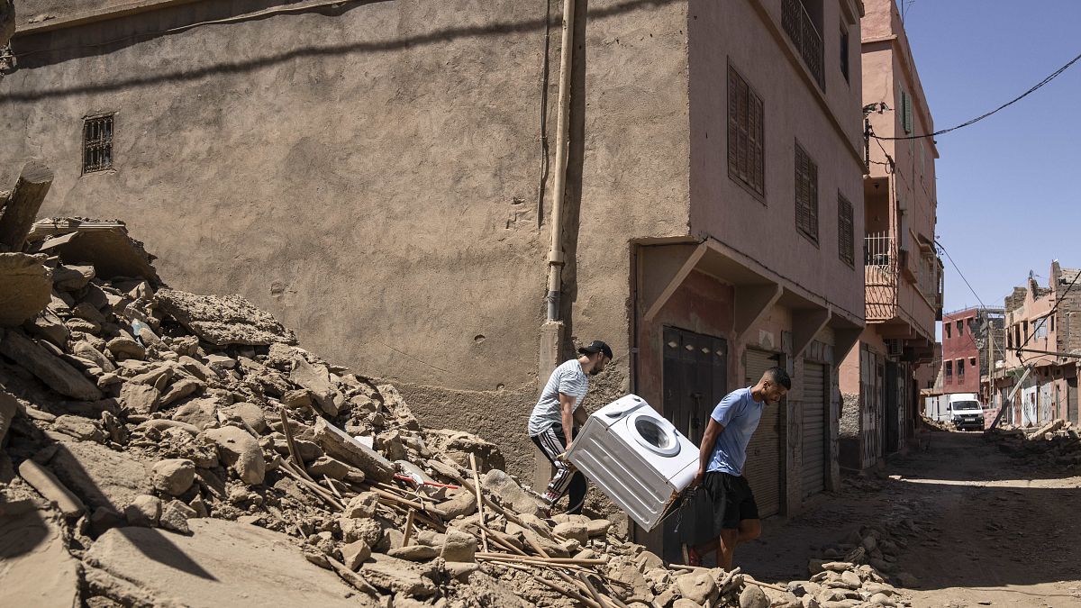 Местные жители выносят стиральную машину из разрушенного дома. Амизмиз, Марокко. 10 сентября 2023.